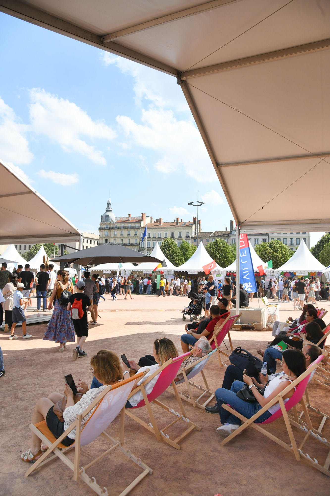 Des personnes profitant d'un espace ombragé sur nos transats pour les fêtes consulaires de la ville de Lyon, place Bellecour en juin 2023